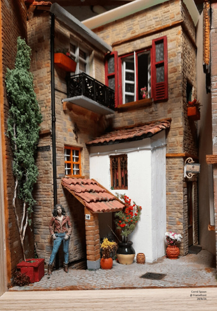 A European style book nook representing a miniature old street facade with a tiny balcony and a figure