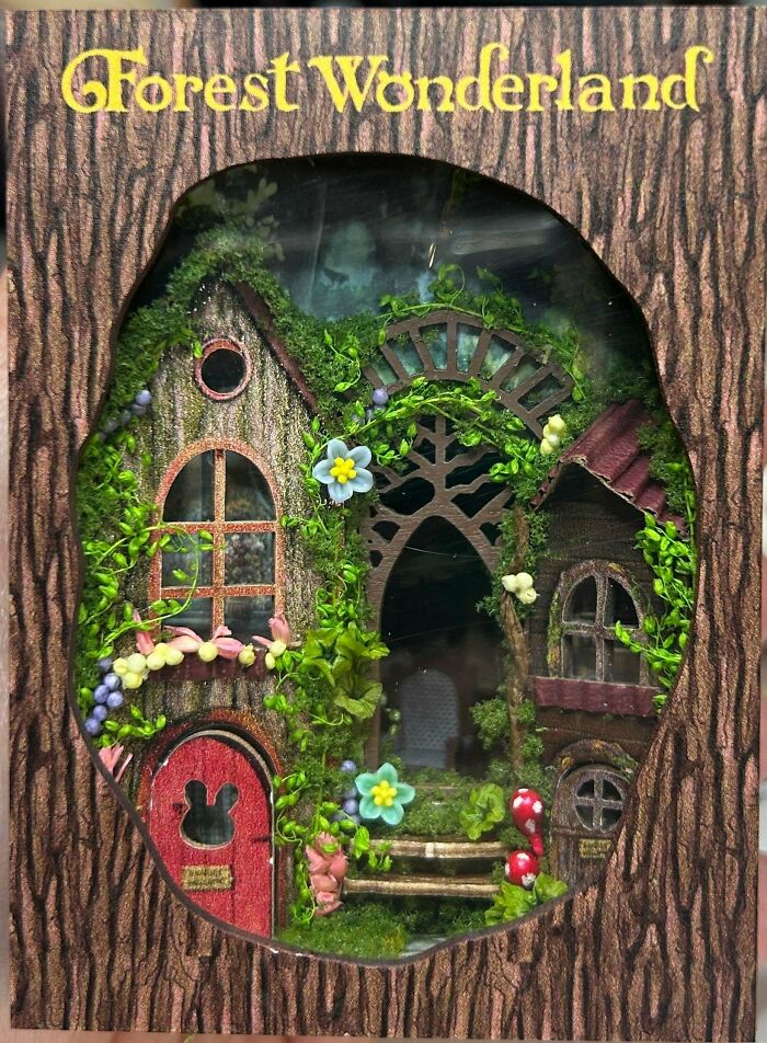 A whimsical forest wonderland book nook with tiny cottages, moss, and fairy doors