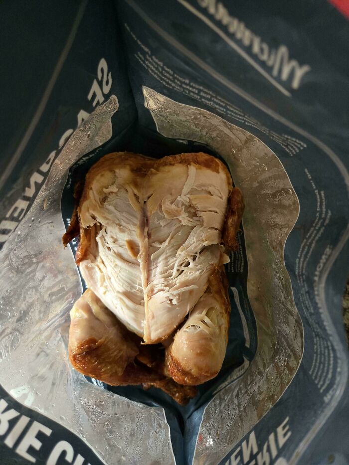 A roasted chicken inside a plastic container with only the breast skin eaten, showing funny things wives do.