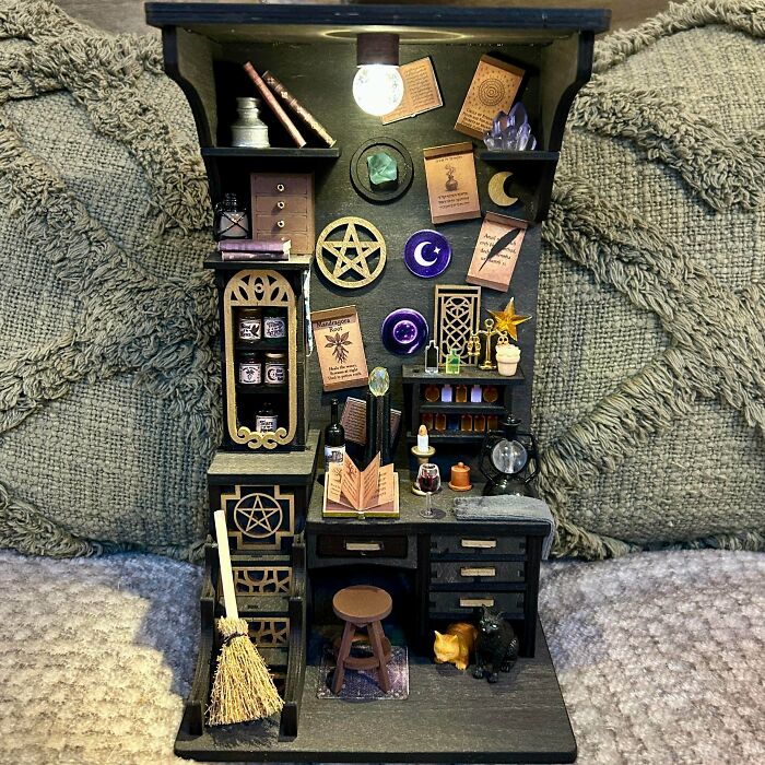 A witchy witchcraft-themed book nook featuring miniature magic potions, a spell book, and a tiny broom.