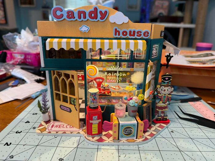 Colorful miniature candy house dollhouse shop with striped awning, gumball machine, and sweets