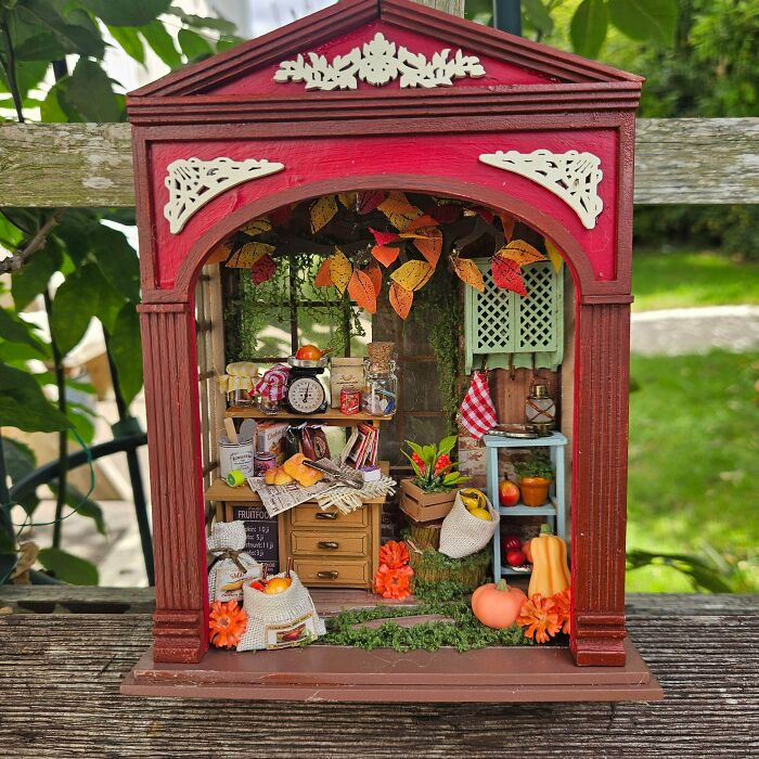 An autumn-themed miniature kitchen book nook featuring pumpkins, fall leaves, and tiny kitchen details.
