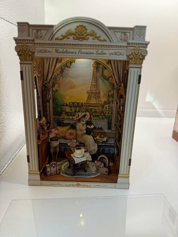An elegant Parisian book nook featuring a cat reading on a balcony with the Eiffel Tower in the background