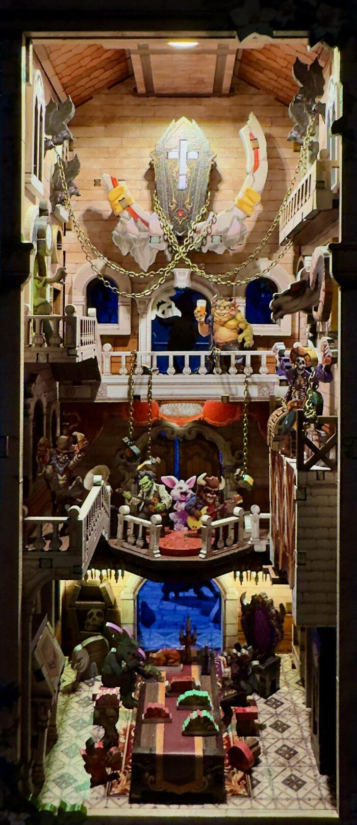 A fantasy tavern book nook with mini-figures on multiple levels and a lit stage