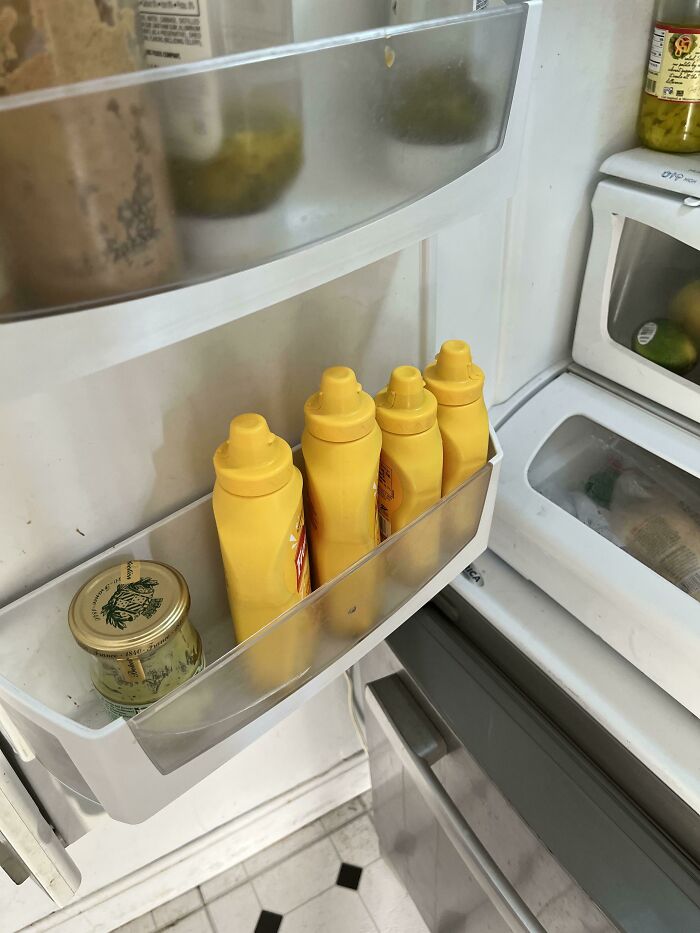 Four mustard bottles lined up in a fridge door, showing funny habits wives have