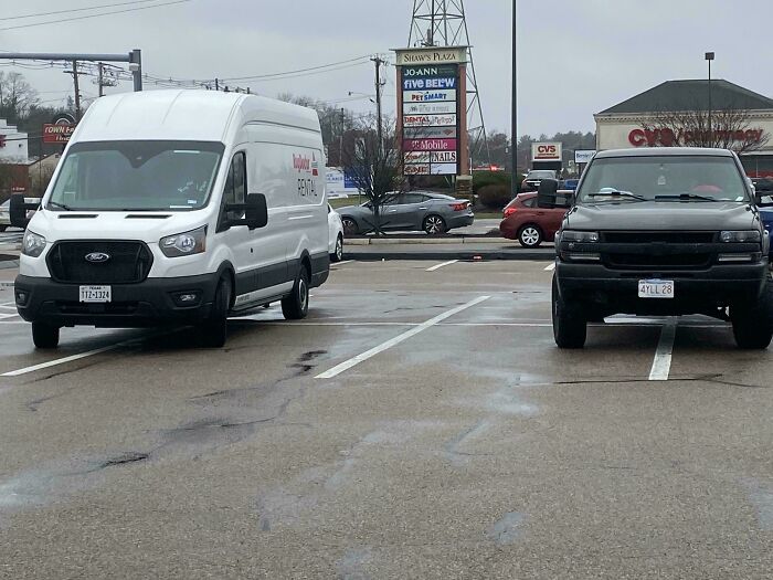 A white rental van and a black truck parked badly, showcasing how entitled people take up multiple spaces.