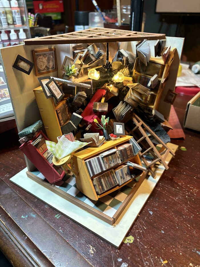 A chaotic miniature library book nook with shelves and loose pages
