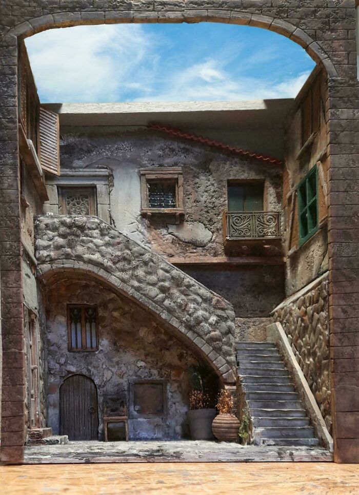 A detailed Mediterranean-style village book nook featuring stone stairs and archway