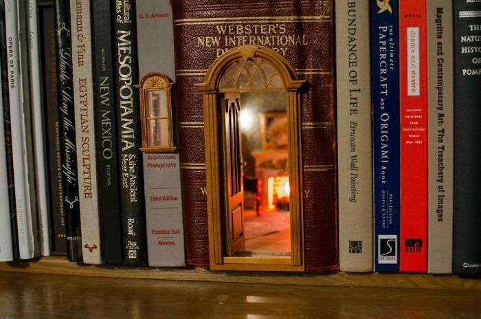 A creative book nook with a miniature open door and window in a hollowed book