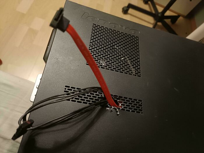 Computer tower with red wires pulled through a roughly cut hole in a questionable DIY projects attempt.