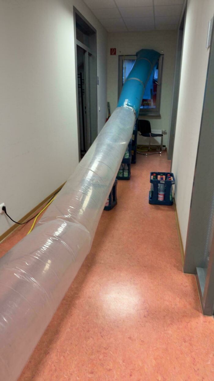 Long plastic ventilation tube stretched through an indoor hallway as part of questionable DIY projects.
