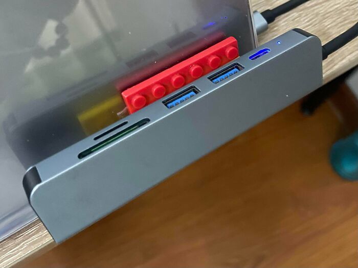 Computer USB hub wedged into place using a red toy brick for questionable DIY projects