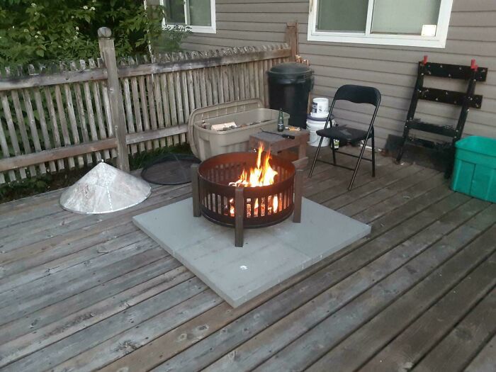 A fire pit placed on stone tiles on a wooden deck as part of questionable DIY projects.