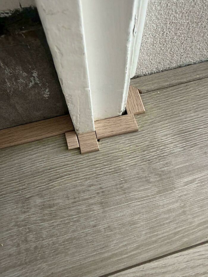 Poorly fitted laminate flooring filled with tiny wood scraps around a door frame in a questionable DIY project.