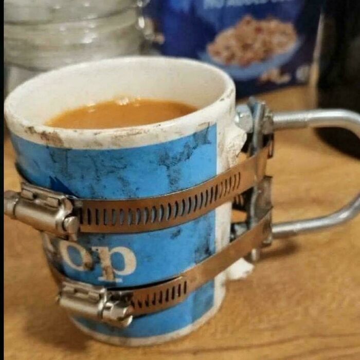 A cracked coffee mug held together with hose clamps, demonstrating questionable DIY projects.