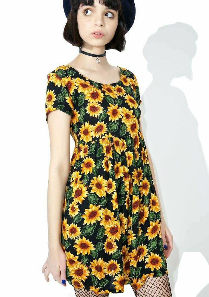 A young woman modeling a classic 1990s style sunflower print dress with a black choker necklace