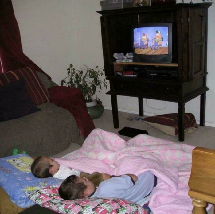 Two kids lying on the floor watching cartoons on a CRT television, reminiscing about the 90s.