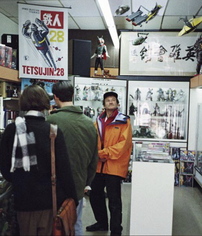 Robin Williams looking around a retro Japanese toy shop filled with action figures and posters from the 90s
