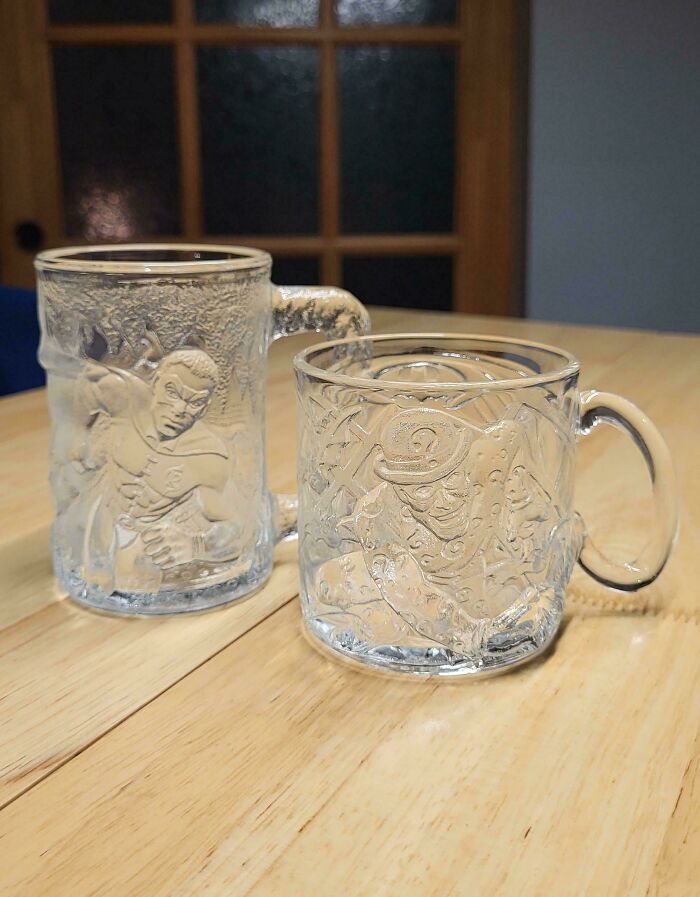 Two clear glass McDonald's Batman Forever mugs showing Riddler and Robin characters from the '90s.
