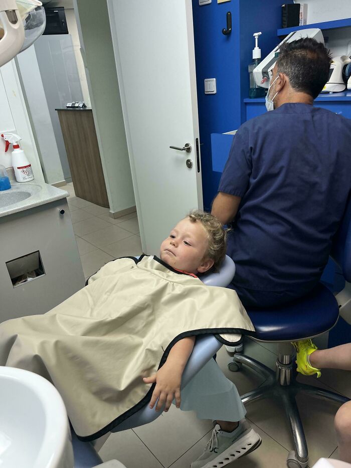 A toddler reclining in a dental chair during an appointment, showcasing wholesome pics of dads supporting kids