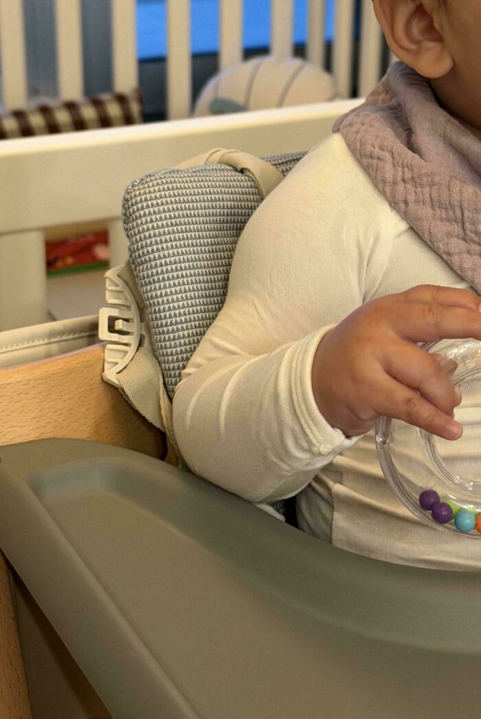 A close up of a baby holding a toy in a high chair, featured in wholesome pics of dads sharing sweet moments.