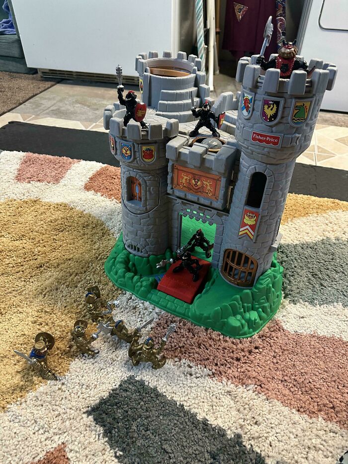 A toy castle setup on a rug with knight action figures, showcasing wholesome pics of dads sharing fun games with kids