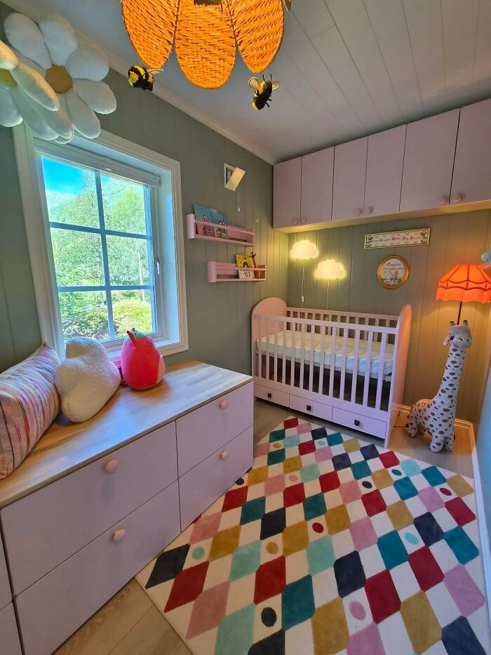 A cozy and colorful nursery decorated by dads nailing fatherhood with a pink crib, dresser, and harlequin rug.
