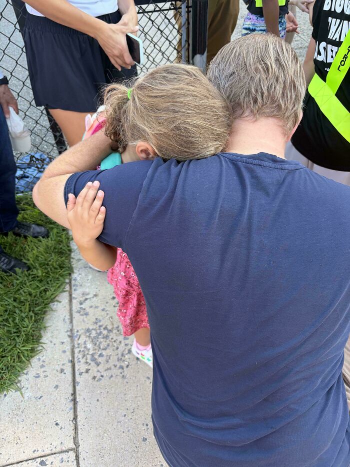 A wholesome moment of a dad comforting his young daughter with a warm hug