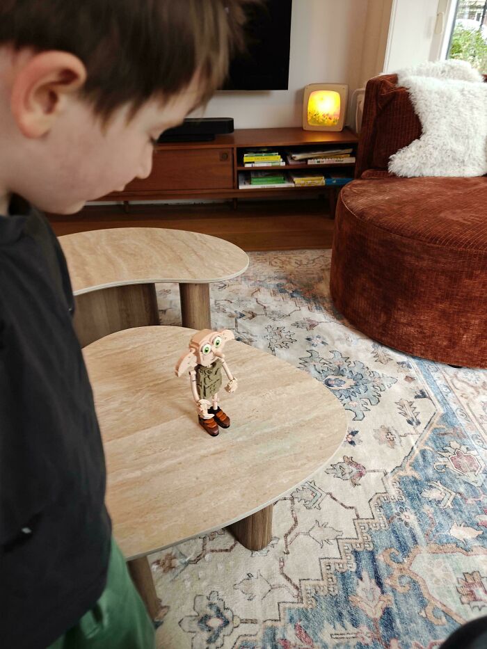 A child looking at a toy figure on a table showcasing wholesome fatherhood and parenting moments