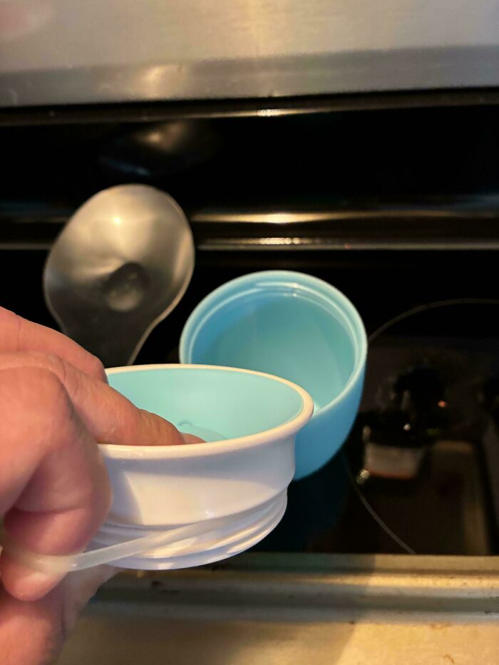 Person holding a blue and white silicone cup lid, showcasing a practical device in wholesome pics of dads.