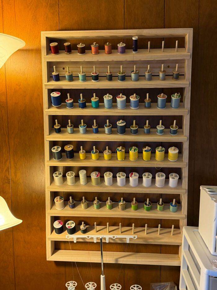 Handmade wooden thread spool rack mounted on a wall, showing wholesome pics of dads crafting projects.