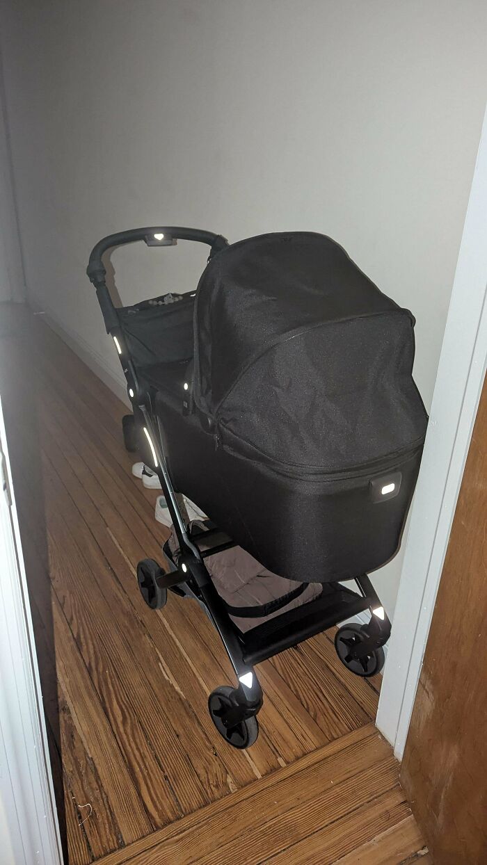 A modern black stroller parked in a hallway, representing wholesome pics of dads preparing for walks.