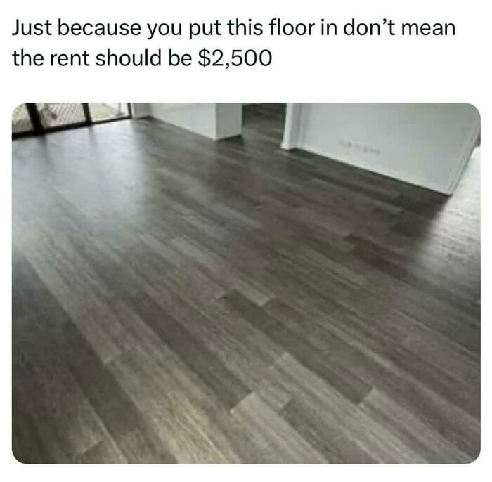 Grey laminate flooring in an apartment mocking terrible landlords who overcharge rent for cheap renovations.