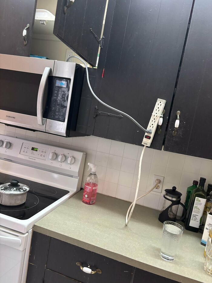 A poorly installed microwave power strip setup by terrible landlords in a kitchen