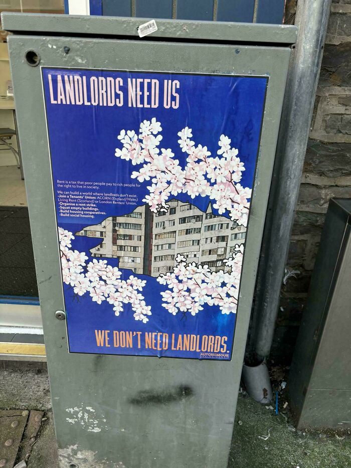 Protest poster stating Landlords Need Us, We Don't Need Landlords, taped to a utility box.