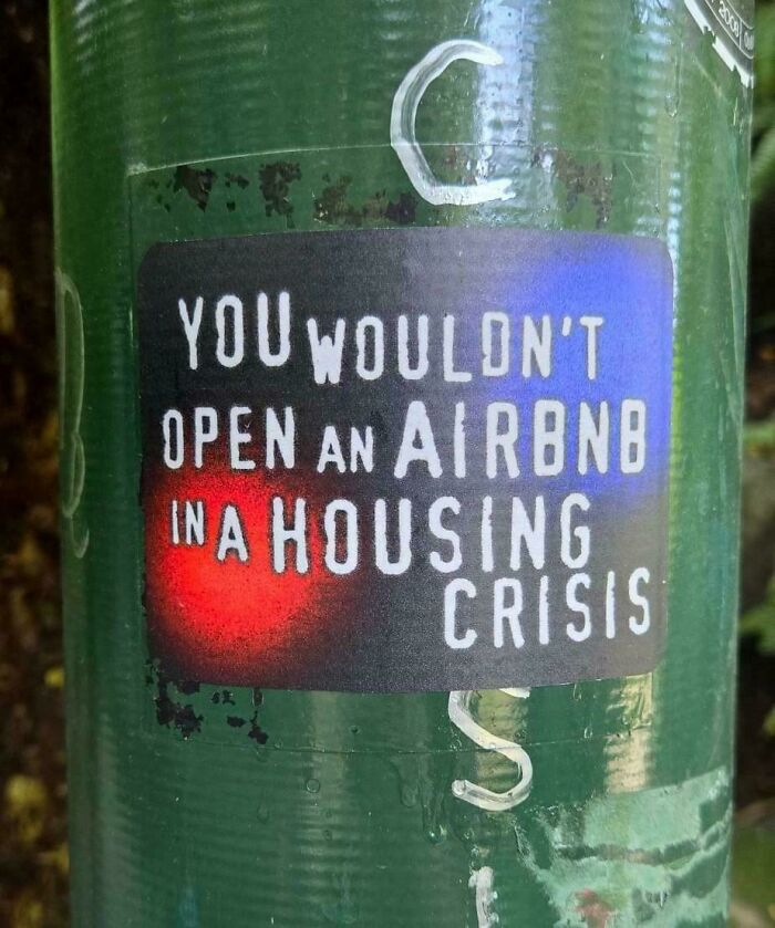 A sticker protesting short term rentals during a housing crisis, highlighting issues with landlords.