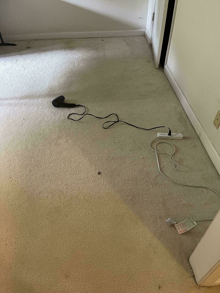 Dirty room with a hairdryer plugged into a power strip on the floor, showing a terrible landlord neglect
