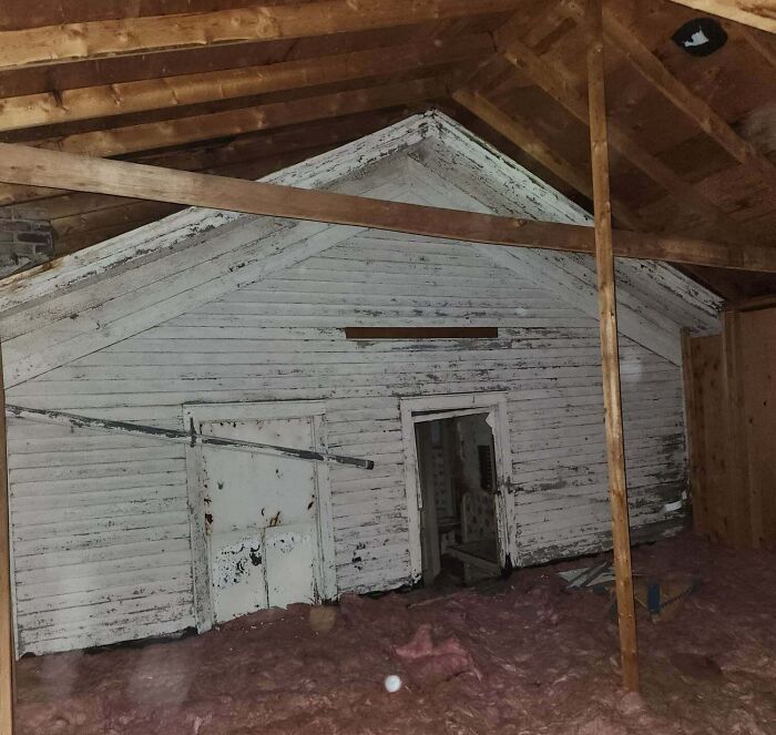 A cool photo showing a preserved old house facade hidden inside a modern attic space.