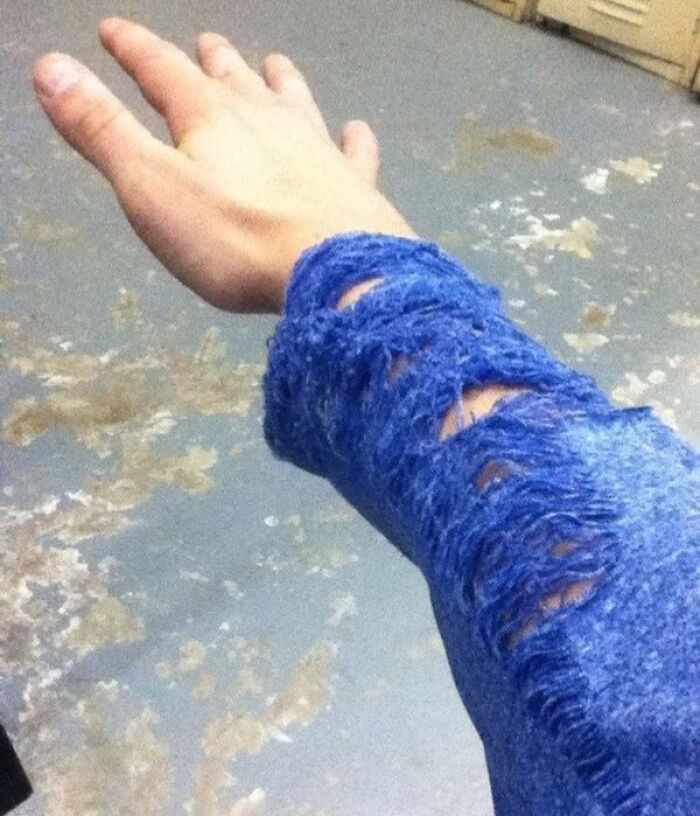 A hand wearing a blue sweater with frayed, sliced sleeves, demonstrating interesting and cool photos