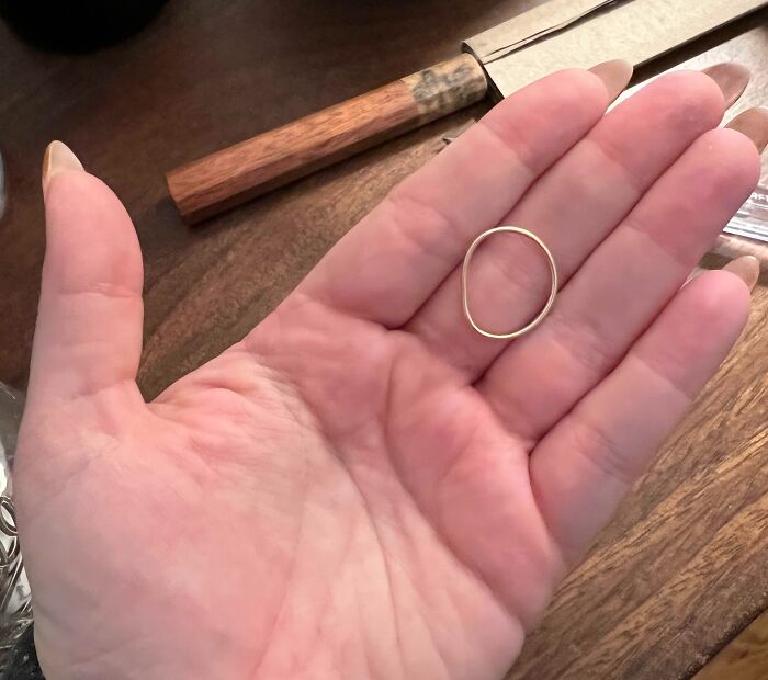 Cool photos of a tiny golden ring resting on a person’s open palm