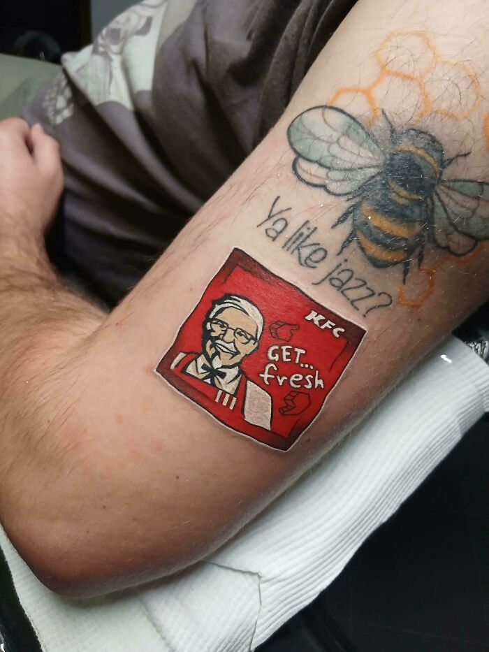 An arm tattoo featuring a bee and Colonel Sanders logo, examples of awful to look at creations.