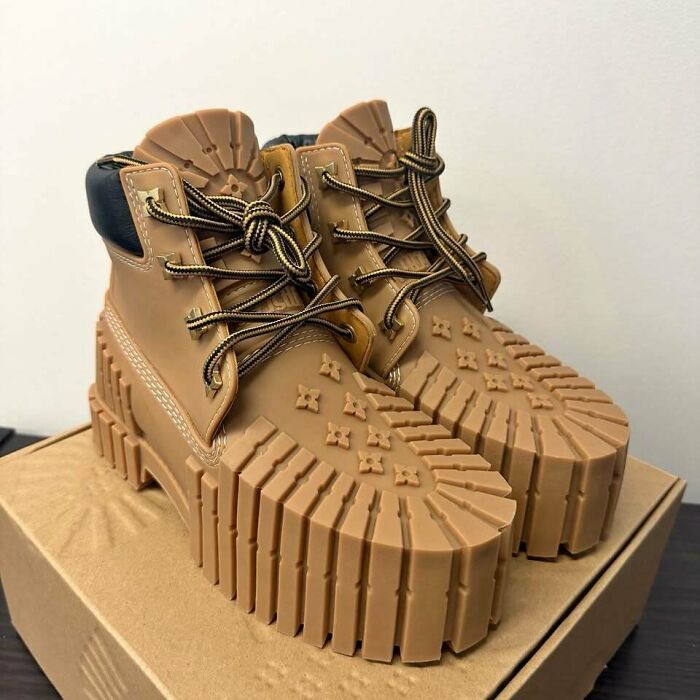 Awful creations featuring tan work boots with unusually thick ribbed soles on top of a box.