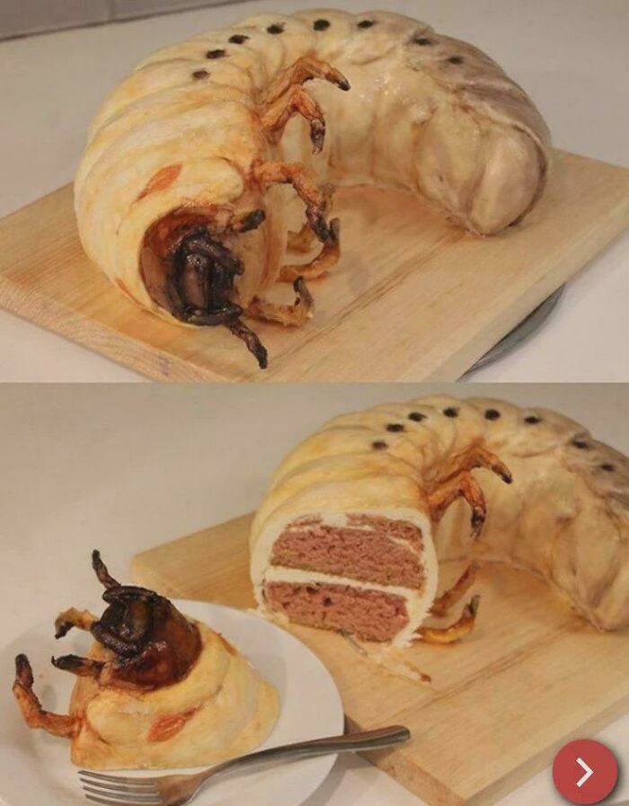 A realistic giant grub cake creation, well-made yet awful to look at, sliced open on a board.