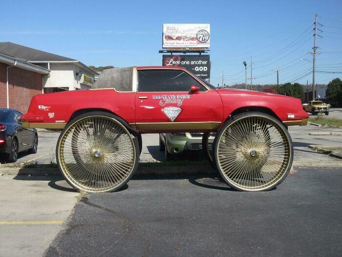 A red car with oversized spoked wheels showcasing unusual creations.