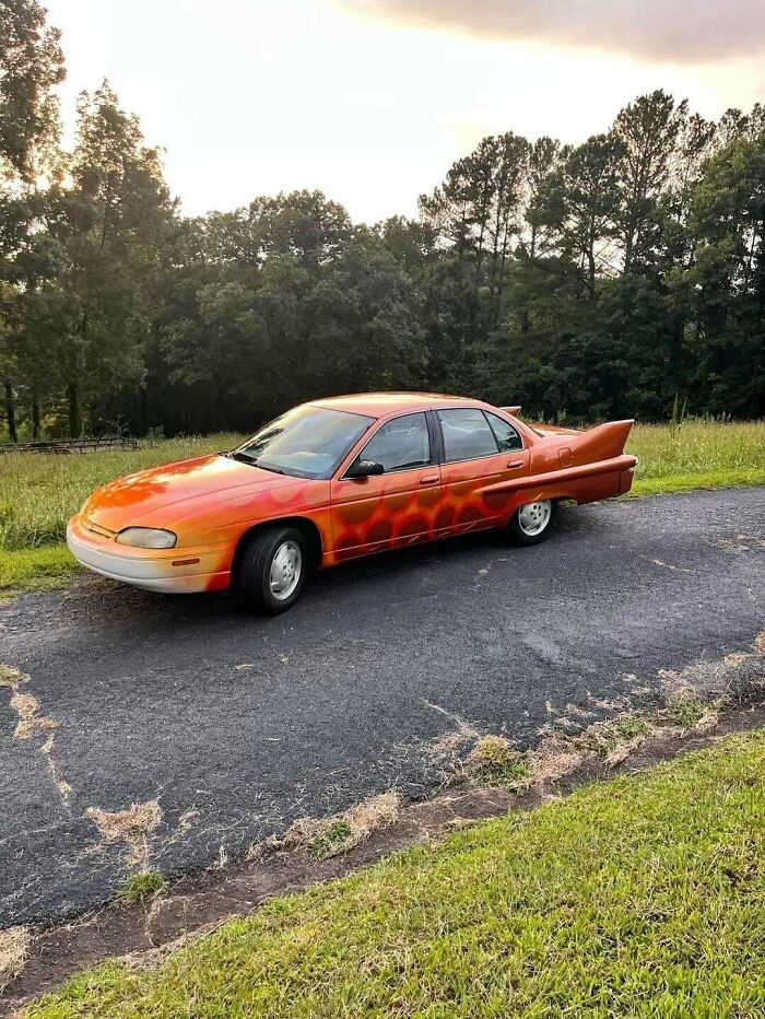 Custom orange painted car with rear fins parked outside, among creations awful to look at but well-made.