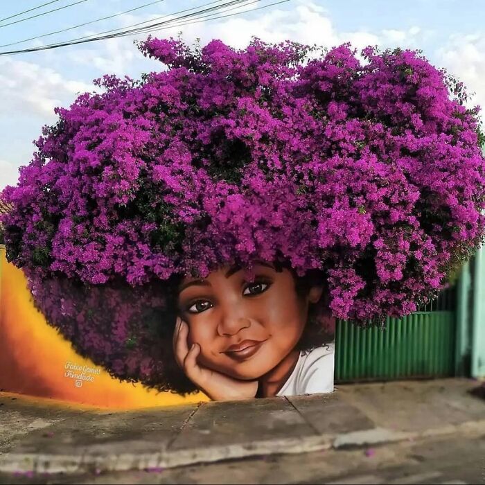 A captivating street art mural of a girl with vibrant purple flowers for hair, a stunning example of urban art.