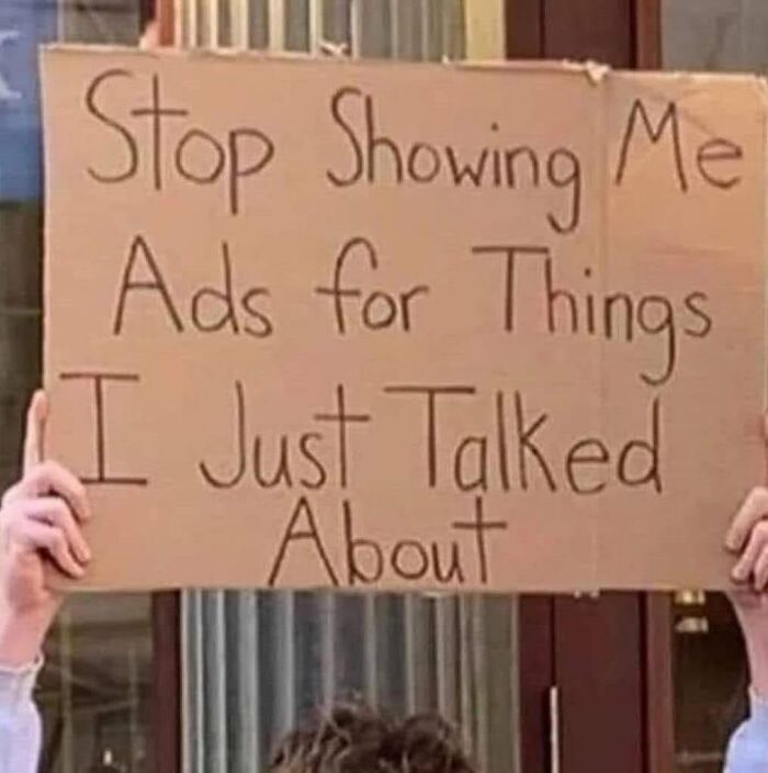 A person holding a cardboard sign with a funny message: Stop Showing Me Ads for Things I Just Talked About.