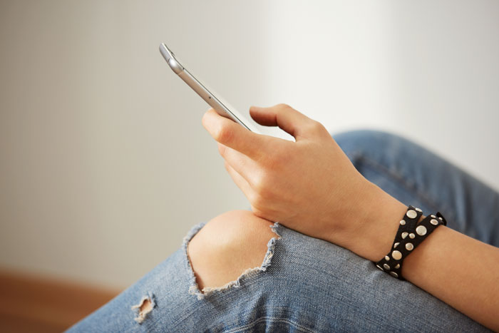 A woman messaging on her phone, illustrating how relationships can turn into headaches.