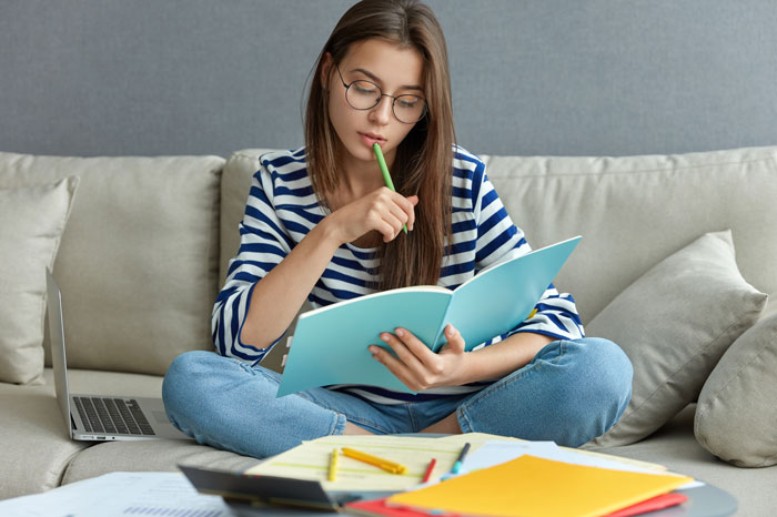 A woman sitting on a couch, focused on a book, reflecting on women doing crazy things for a crush.