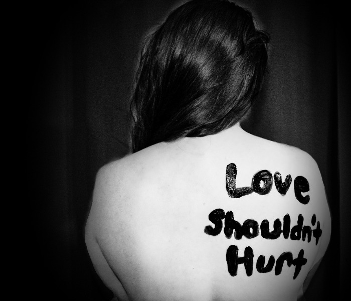 Back of a woman with 'Love Shouldn't Hurt' written on her back, raising awareness about a man's brutal reaction. Back of a woman with 'Love Shouldn't Hurt' written on her back, raising awareness about a man's brutal reaction.